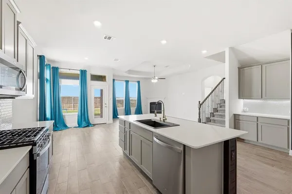 a kitchen that has a lot of cabinets a sink and wooden floor