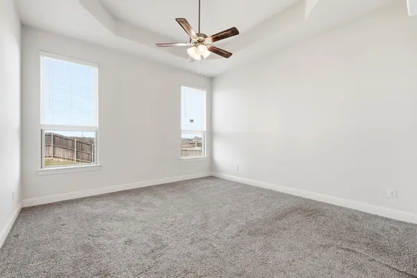 an empty room with windows and ceiling fan