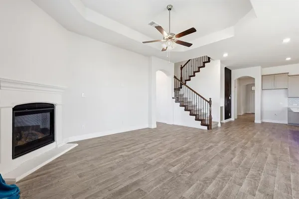 a view of an empty room with wooden floor fireplace and a window
