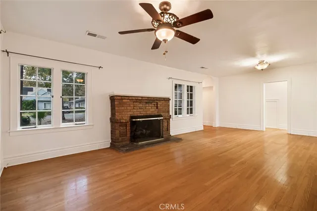 an empty room with windows fireplace and a ceiling fan