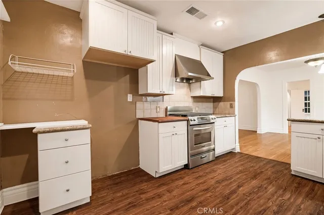 a kitchen with a stove cabinets and wooden floor