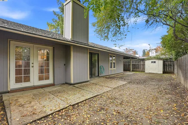 a backyard of a house with large trees and wooden fence