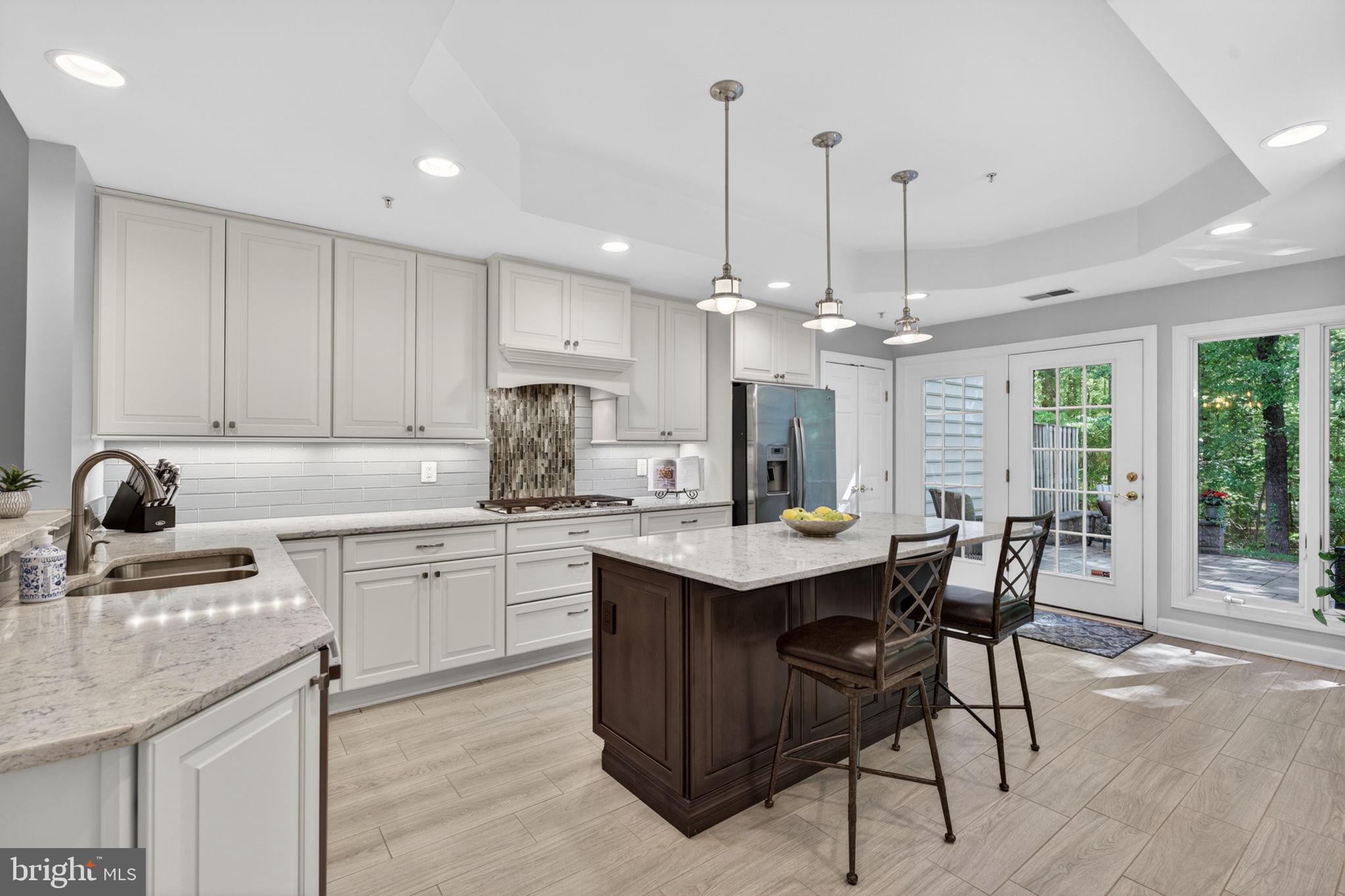 336 Colony Point Place Edgewater, MD 21037 - Photo 20 of 40 a kitchen with stainless steel appliances granite countertop a sink a stove a kitchen island with chairs and wooden floor
