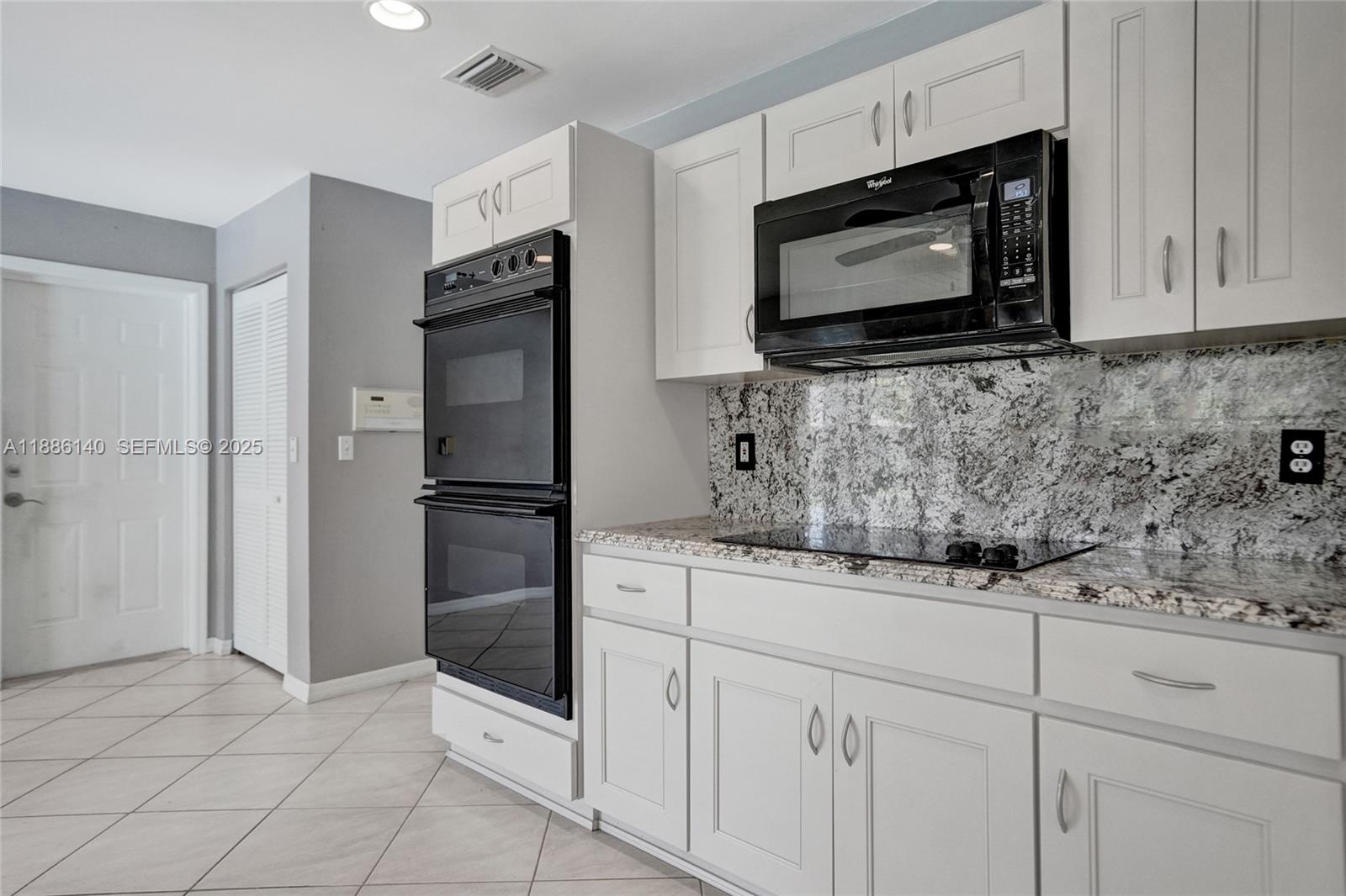 14940 Southwest 164th Terrace Miami, FL 33187 - Photo 32 of 73 a kitchen with granite countertop white cabinets stainless steel appliances and a counter space