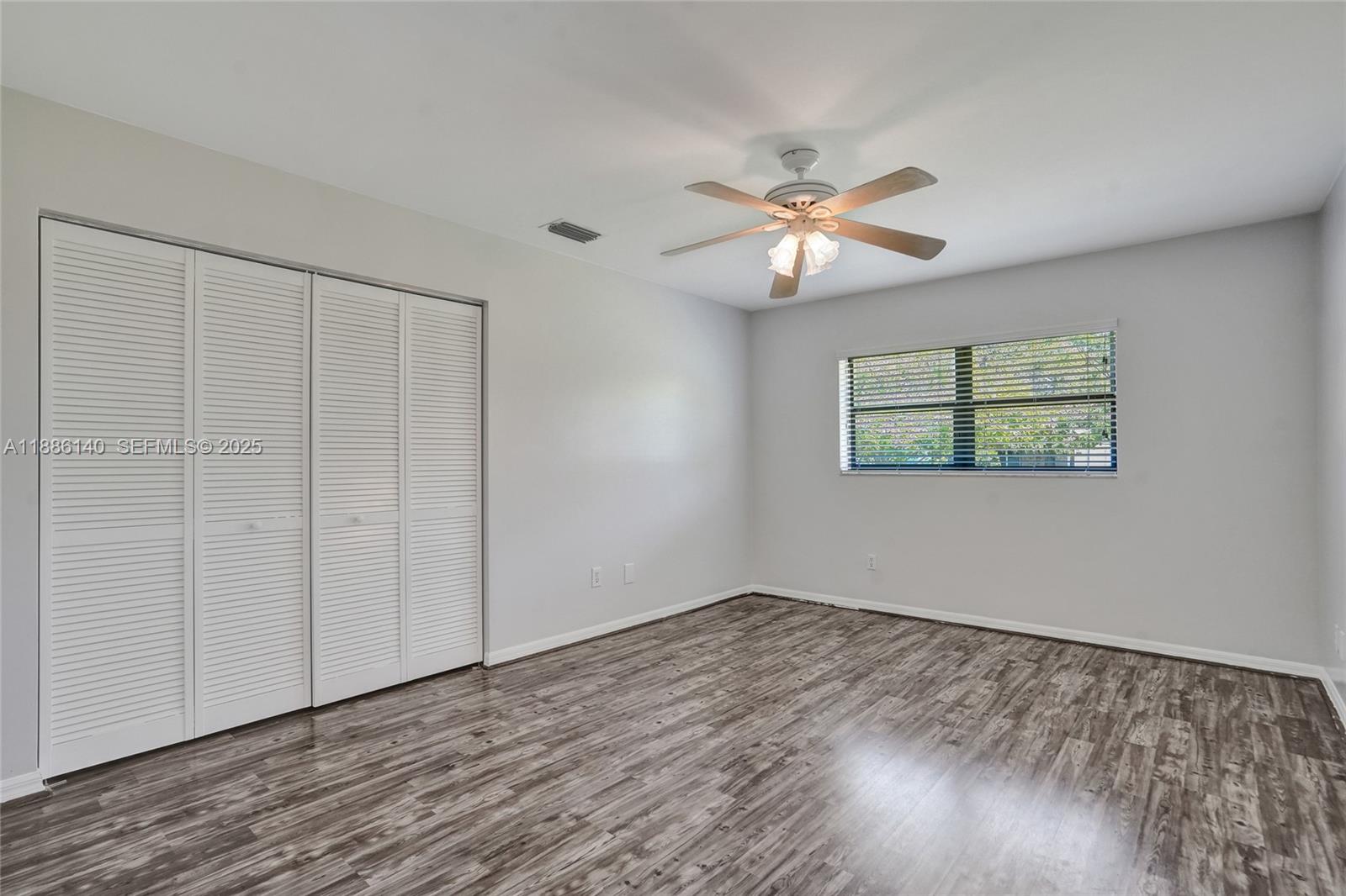 14940 Southwest 164th Terrace Miami, FL 33187 - Photo 46 of 73 an empty room with wooden floor chandelier fan and windows