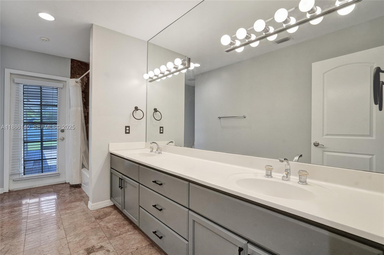 14940 Southwest 164th Terrace Miami, FL 33187 - Photo 53 of 73 a bathroom with double vanity sinks a vanity a lamp and a mirror