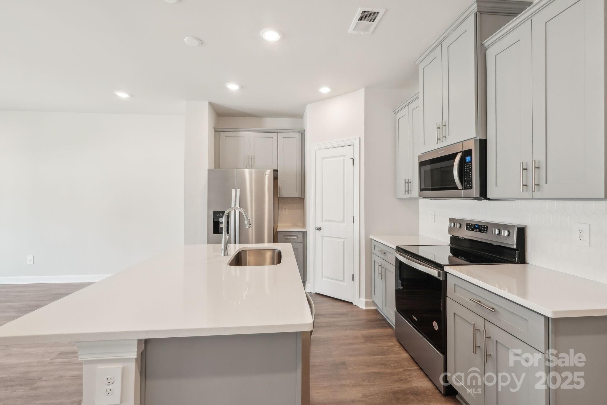 254 Tiger Lily Drive Fort Mill, SC 29708 - Photo 7 of 18 a kitchen with stainless steel appliances kitchen island granite countertop a refrigerator a stove and a sink with wooden floor