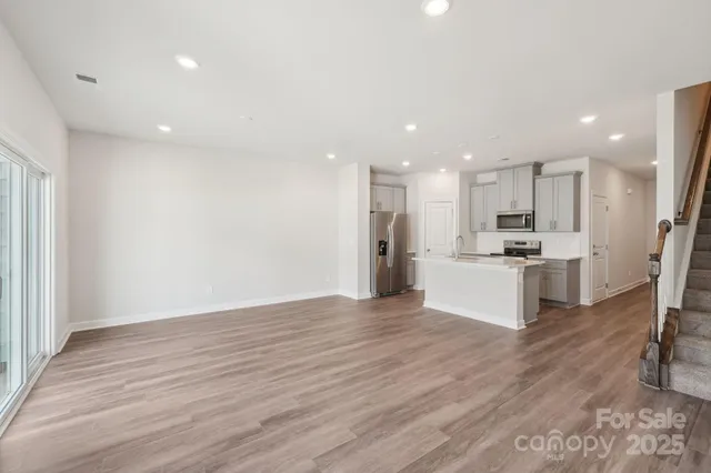 a view of kitchen with kitchen island a sink wooden floor and stainless steel appliances