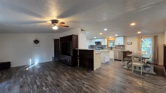 a open kitchen with cabinets a sink dishwasher a dining table and chairs with wooden floor