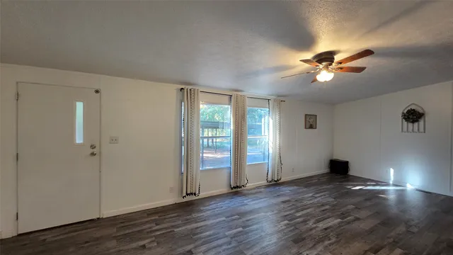 a view of an empty room with a window and wooden floor