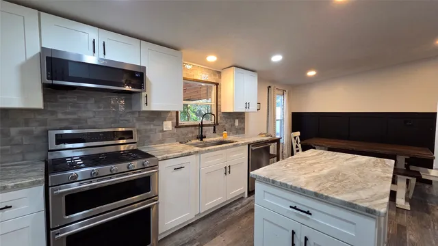 a kitchen with stainless steel appliances kitchen island granite countertop a stove and a sink