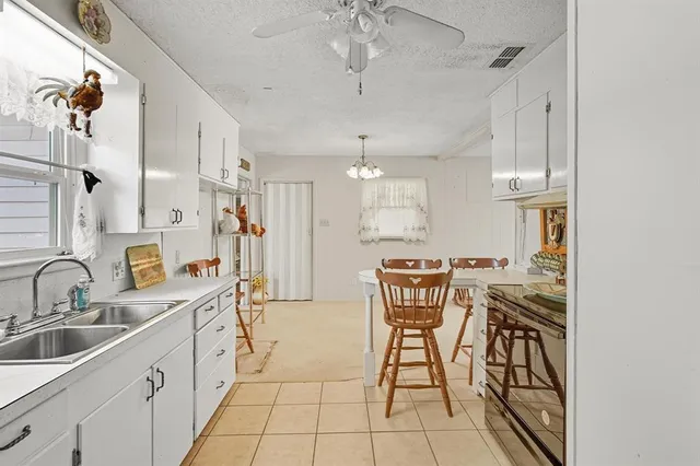a view of a kitchen with kitchen island granite countertop lots of white cabinets and stainless steel appliances