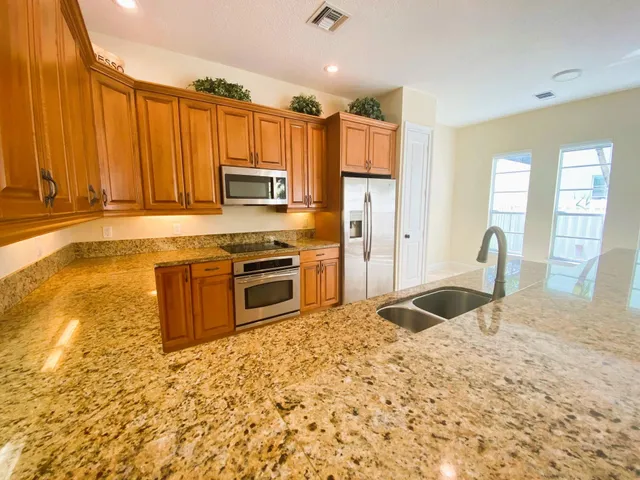 a kitchen with stainless steel appliances granite countertop a stove a sink and a refrigerator