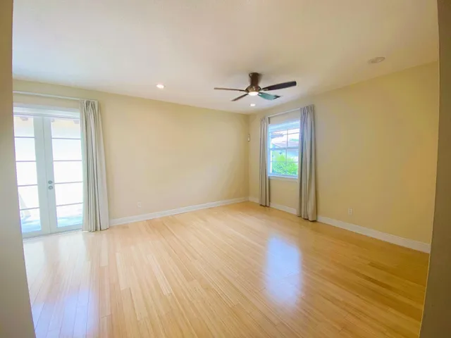 an empty room with wooden floor and windows