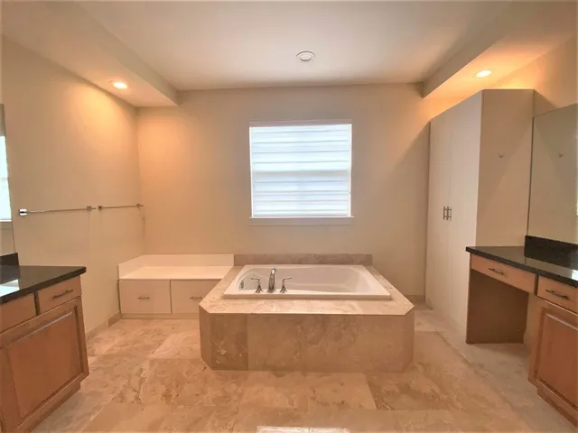 a spacious bathroom with a tub sink and mirror