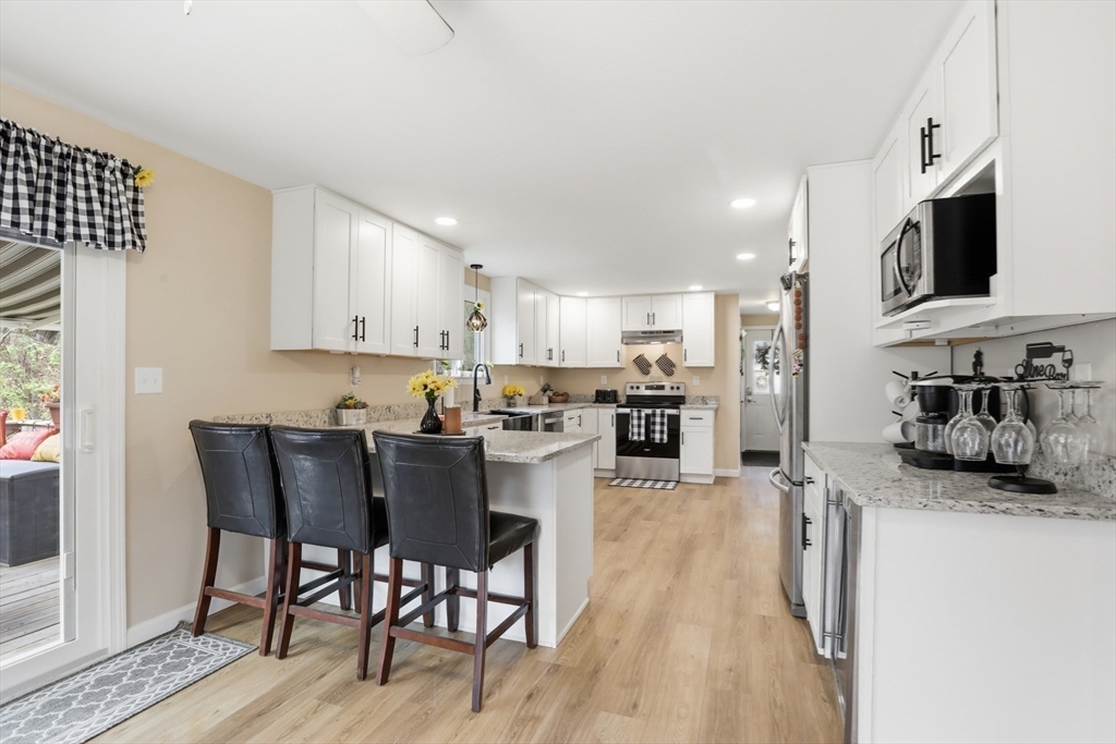 18 Trifiro Road Billerica, MA 01821 - Photo 17 of 42 a kitchen with stainless steel appliances granite countertop a stove top oven a sink a dining table and chairs with wooden floor