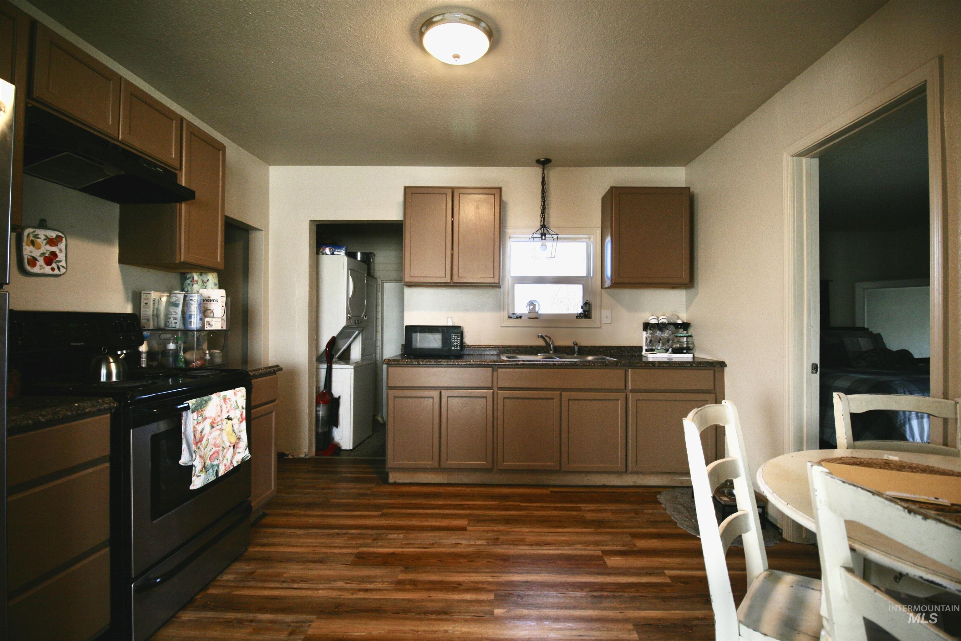 539 North 2nd Street Nyssa, OR 97913 - Photo 9 of 18 Kitchen with stainless steel range with electric cooktop, hanging light fixtures, black microwave, dark wood-type flooring, and a textured ceiling