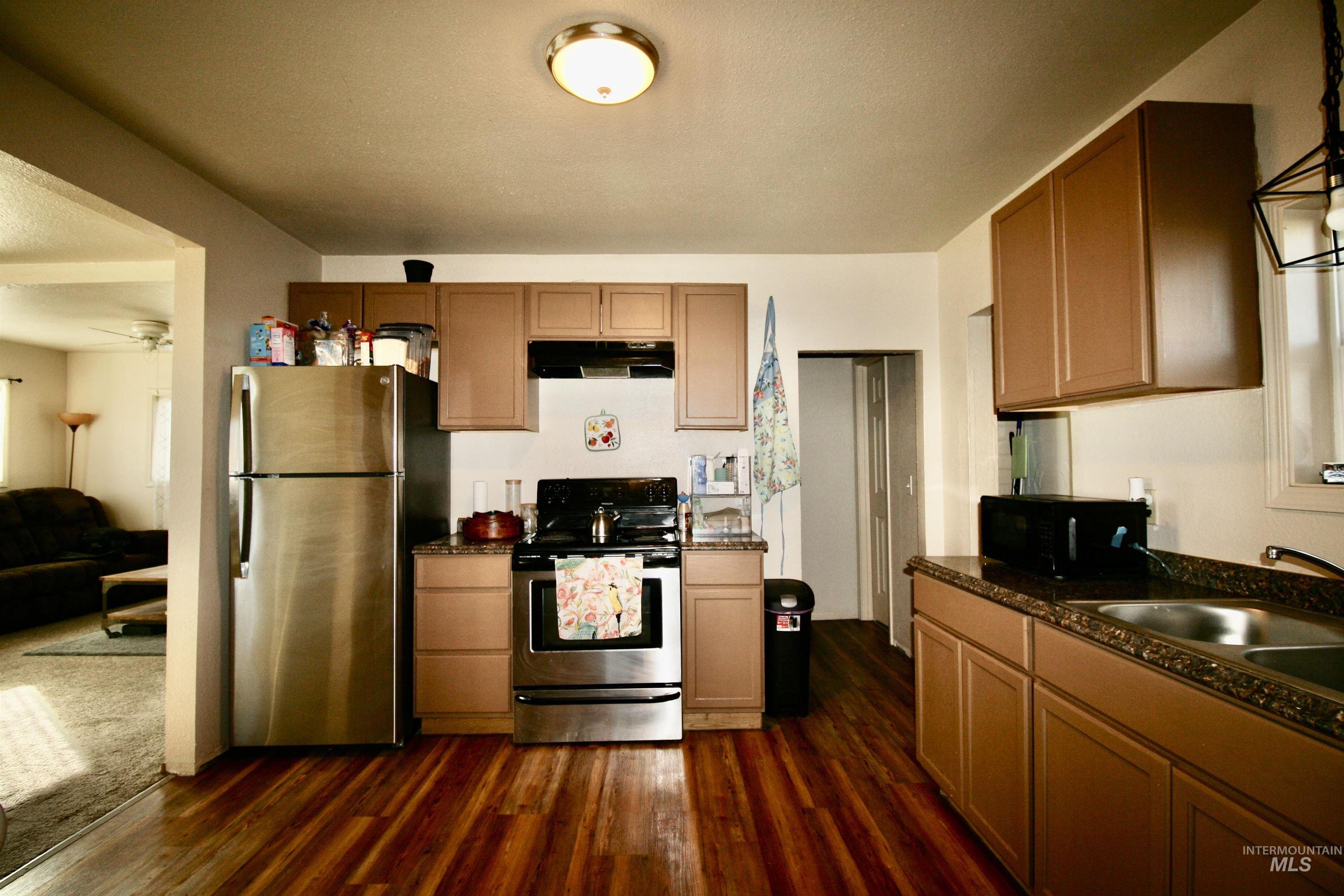 539 North 2nd Street Nyssa, OR 97913 - Photo 10 of 18 Kitchen featuring stainless steel appliances, dark wood finished floors, wood finish cabinetry, and dark stone counters