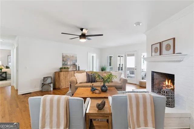 a living room with furniture a fireplace and a ceiling fan