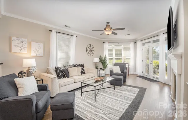 a living room with furniture a large window and wooden floor