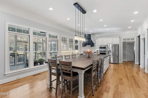 a kitchen with stainless steel appliances kitchen island granite countertop a table chairs and a refrigerator