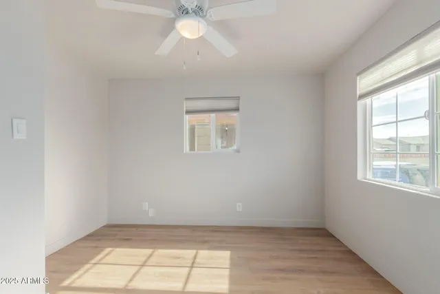 an empty room with a chandelier fan and windows
