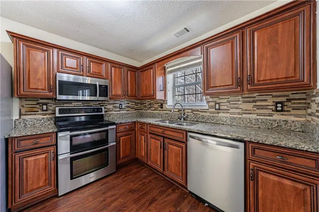 a kitchen with granite countertop wooden cabinets stainless steel appliances and a window