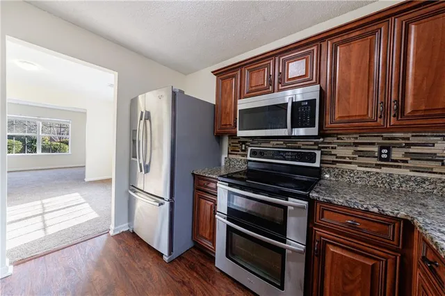 a kitchen with granite countertop a refrigerator stove and microwave