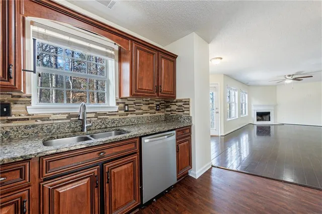 a kitchen with stainless steel appliances granite countertop wooden floors and view of living room