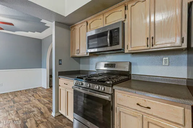 a kitchen with stainless steel appliances granite countertop white cabinets and a stove top oven