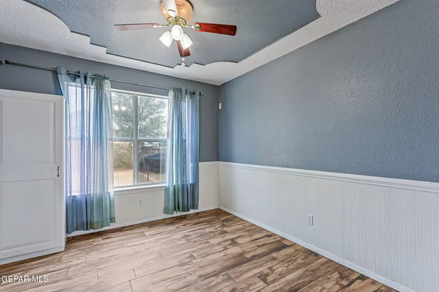 a view of empty room with wooden floor and fan