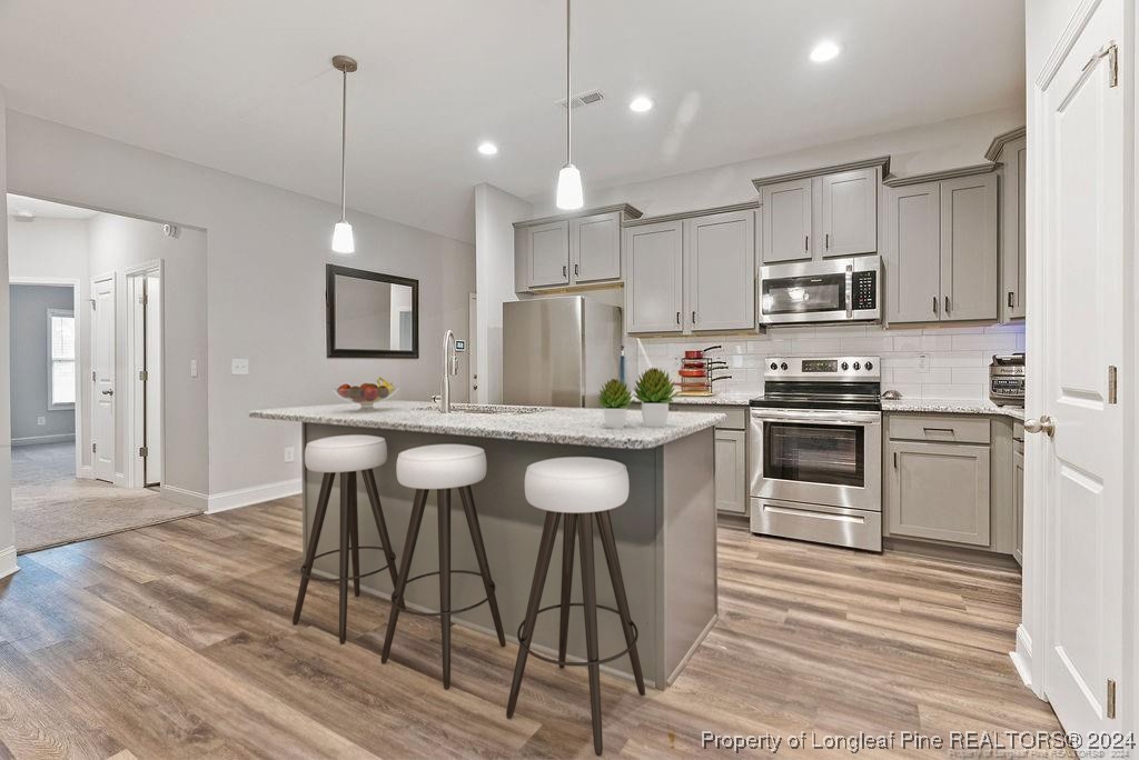 7751 Rufus Johnson Road Fayetteville, NC 28306 - Photo 3 of 21 a kitchen with stainless steel appliances granite countertop a stove a sink a microwave a refrigerator and white cabinets with wooden floor