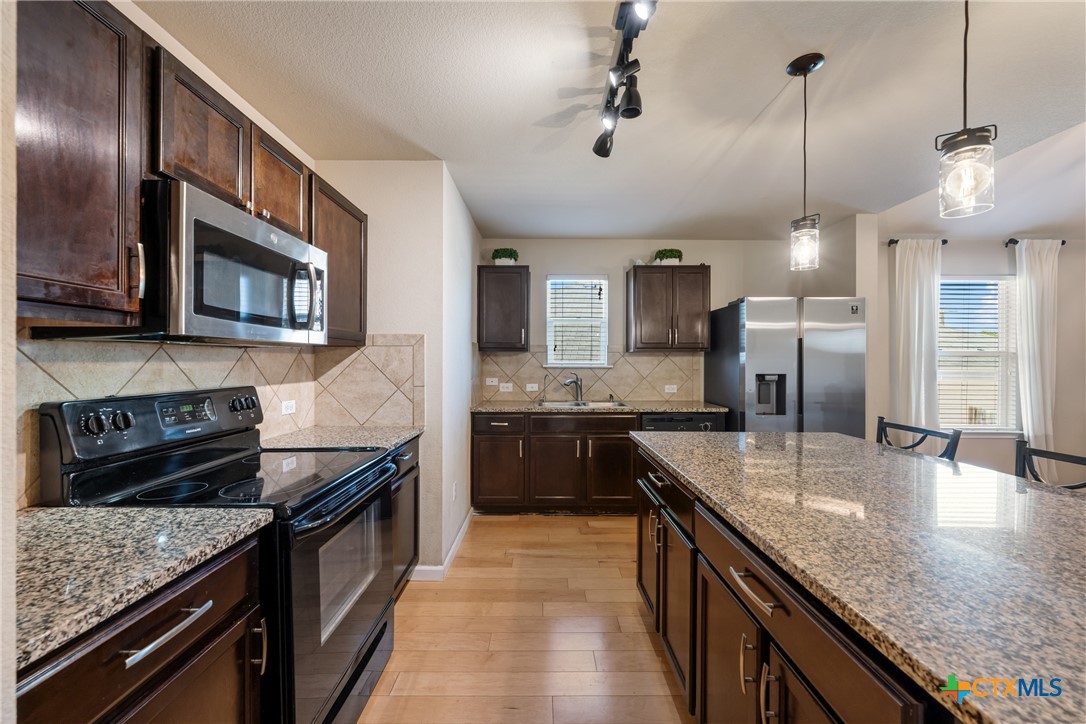117 Liard River Road Hutto, TX 78634 - Photo 7 of 48 a kitchen with stainless steel appliances granite countertop a sink stove and refrigerator