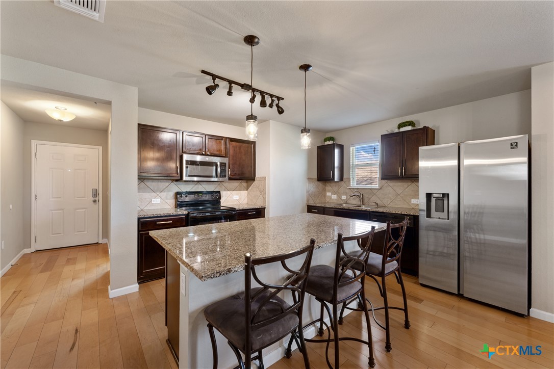 117 Liard River Road Hutto, TX 78634 - Photo 8 of 48 a kitchen with stainless steel appliances granite countertop a refrigerator a stove top oven a sink dishwasher and white cabinets with wooden floor