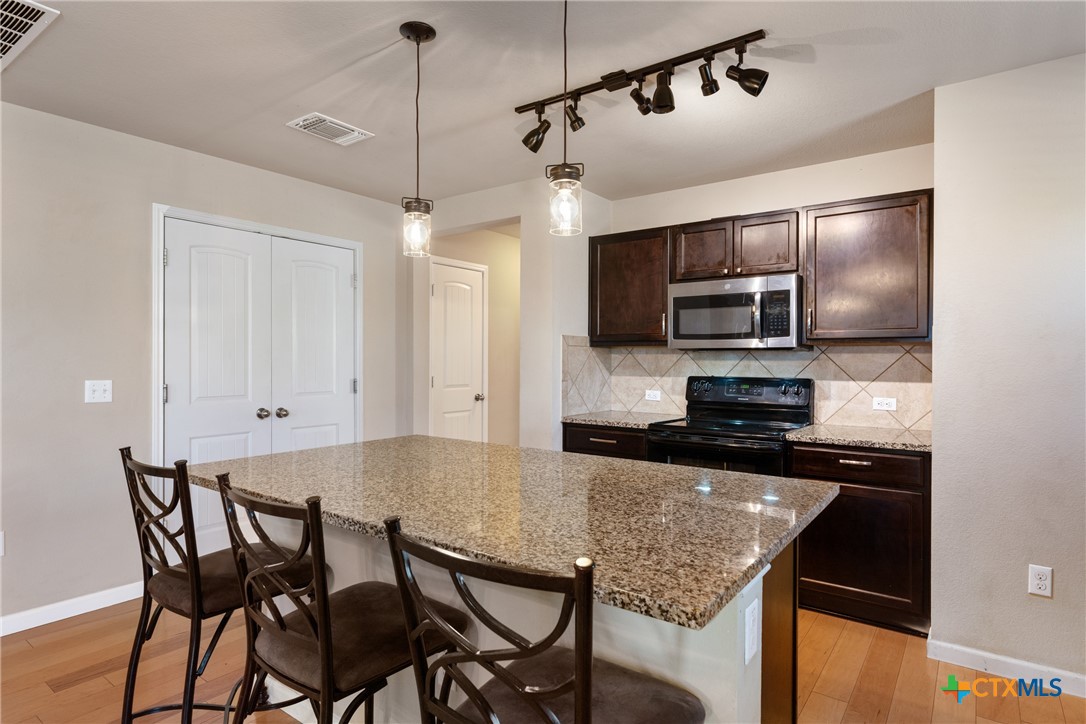 117 Liard River Road Hutto, TX 78634 - Photo 9 of 48 a kitchen with stainless steel appliances granite countertop a sink a stove a microwave with a dining table and chairs