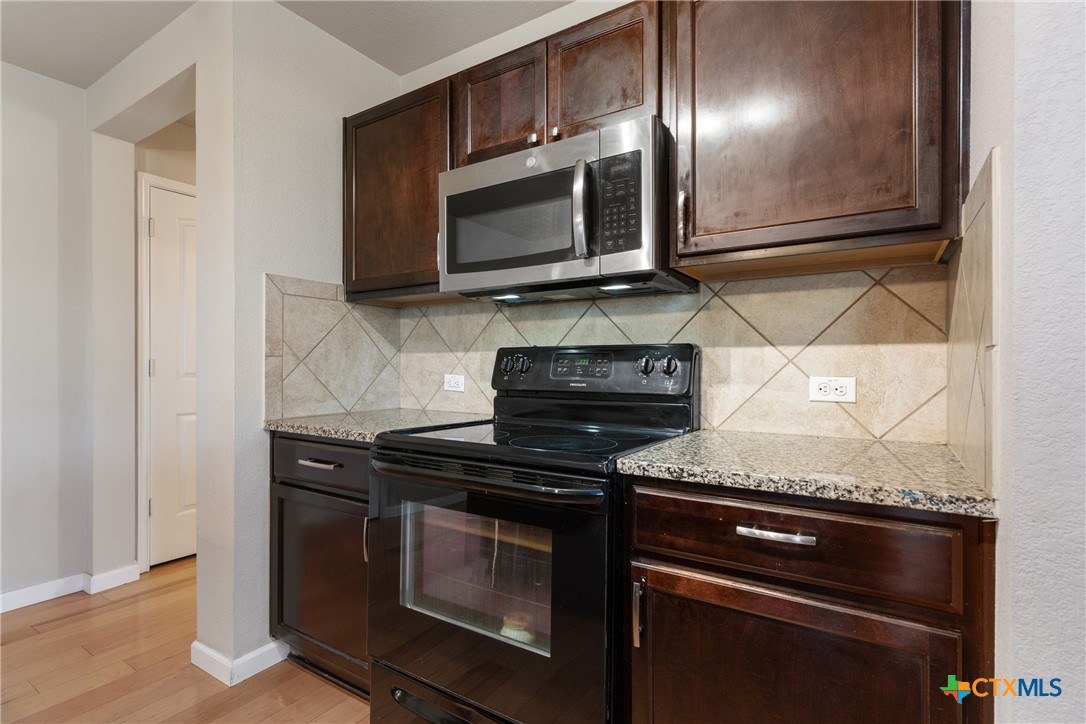 117 Liard River Road Hutto, TX 78634 - Photo 10 of 48 a kitchen with granite countertop cabinets stainless steel appliances and wooden floor