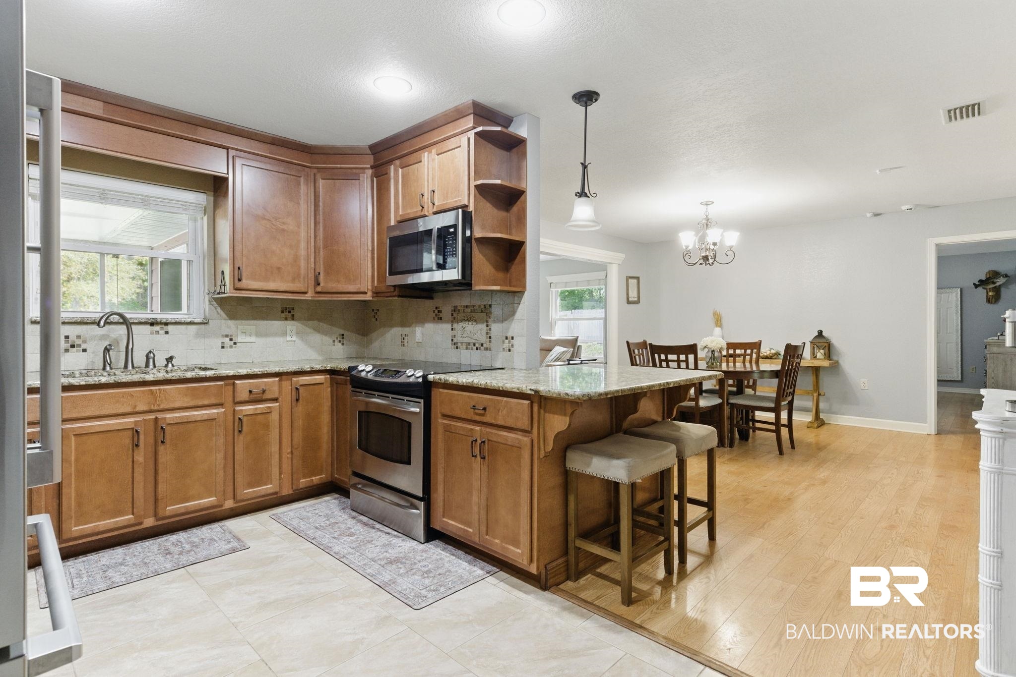 32345 River Lake Road Seminole, AL 36574 - Photo 14 of 56 Kitchen featuring brown cabinetry, a peninsula, open shelves, appliances with stainless steel finishes, and a sink