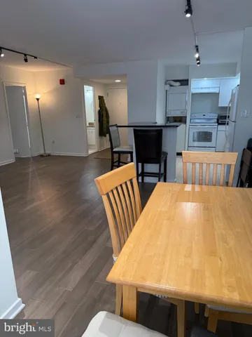 a view of kitchen with stainless steel appliances wooden floor dining table and chairs