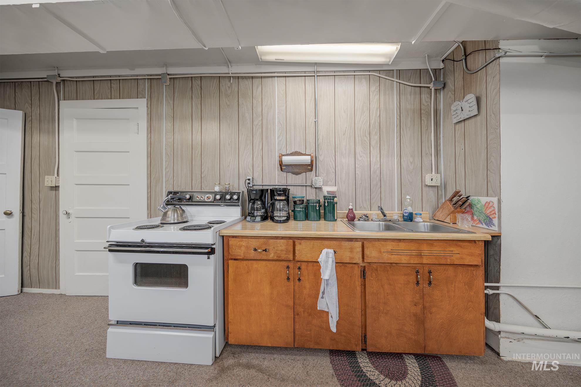 404 North 3rd Street Nyssa, OR 97913 - Photo 23 of 30 Kitchen featuring white electric stove, light countertops, wood walls, wood finish cabinets, and light carpet
