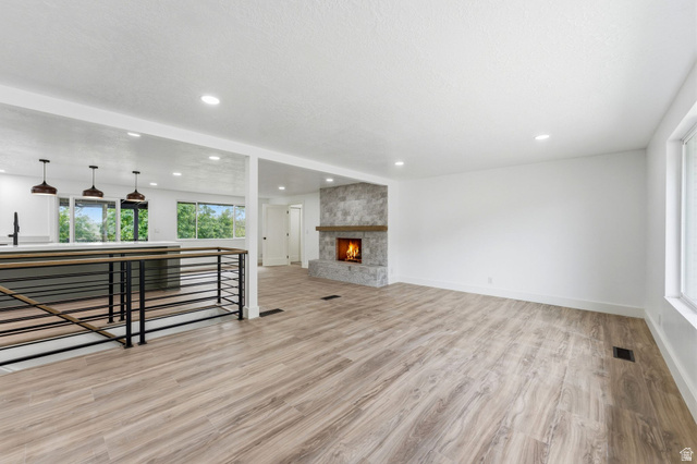 871 Bonita Way Centerville, UT 84014 - Photo 8 of 61 Spacious living area featuring wood-finish flooring, a stone-clad fireplace with a wood mantle, and recessed lighting