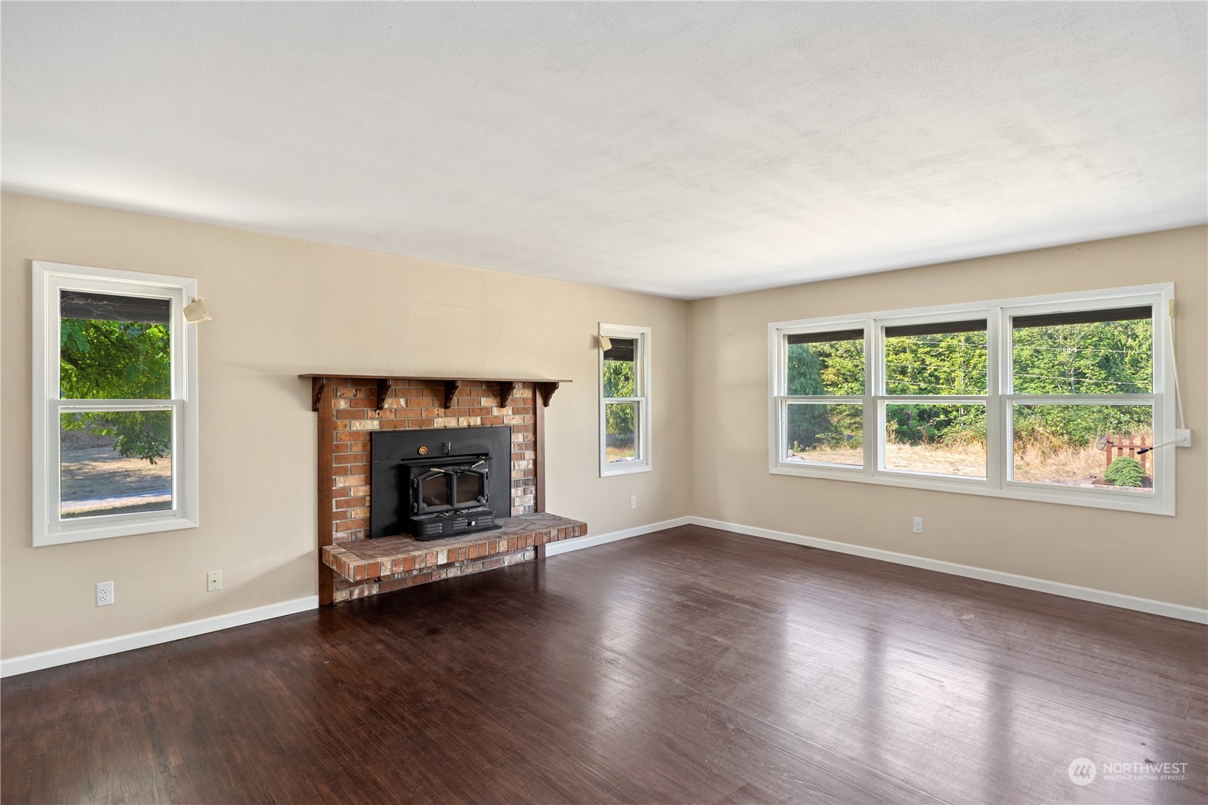 143 Senz Road Sequim, WA 98382 - Photo 7 of 40 an empty room with wooden floor fire place and windows