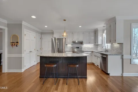 a kitchen with stainless steel appliances granite countertop a kitchen island hardwood floor sink stove and granite counter top