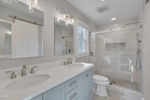 a bathroom with a double vanity sink toilet and shower