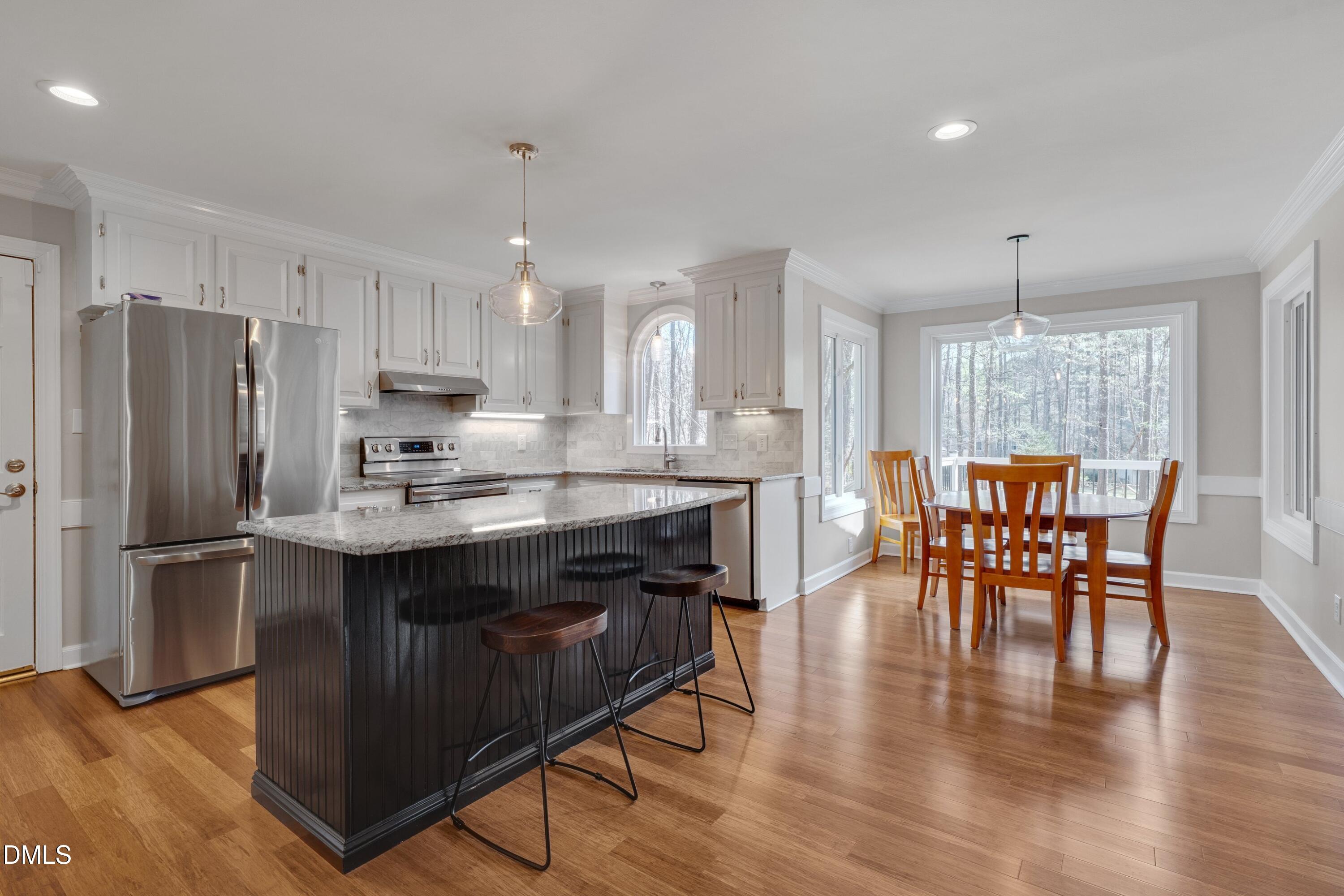 7900 Kingsland Drive Raleigh, NC 27613 - Photo 9 of 32 a kitchen with stainless steel appliances granite countertop a dining table chairs stove refrigerator and cabinets
