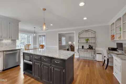 a kitchen with stainless steel appliances granite countertop a kitchen island a stove a sink a dining table and chairs with wooden floor