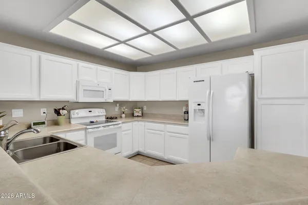 a kitchen with a refrigerator a sink and white cabinets