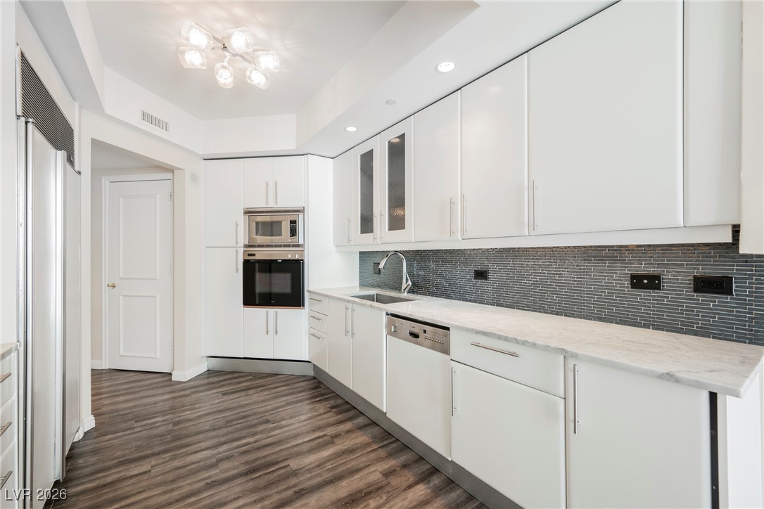 2877 Paradise Road, Unit 1604 Las Vegas, NV 89109 - Photo 11 of 47 Kitchen featuring built in appliances, white cabinetry, backsplash, glass insert cabinets, and recessed lighting