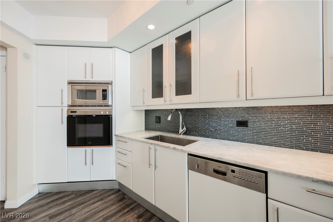 2877 Paradise Road, Unit 1604 Las Vegas, NV 89109 - Photo 14 of 47 Kitchen with stainless steel appliances, white cabinetry, dark wood-style flooring, backsplash, and glass insert cabinets