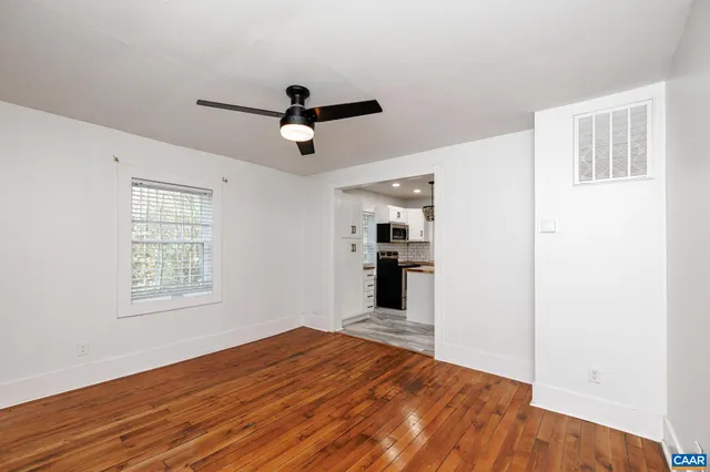 a view of empty room with wooden floor and fan