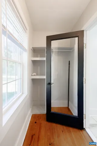 a view of a hallway with wooden floor and cabinet